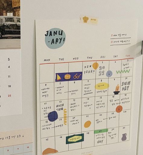 a calendar is hanging on the wall in front of a refrigerator with magnets attached to it