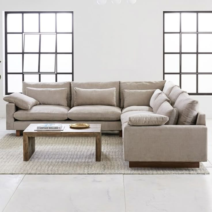 a living room with two couches and a coffee table in front of three windows