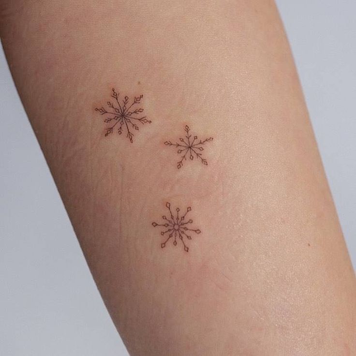 two small snowflakes on the back of a woman's arm