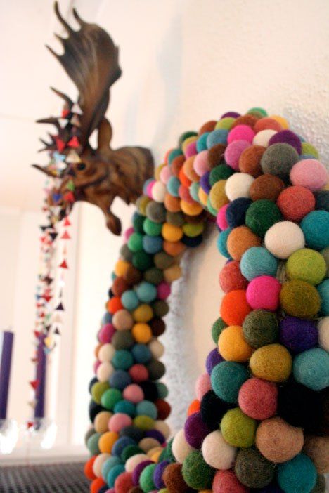 a multicolored wreath is hanging on the wall next to a deer head and other decorations