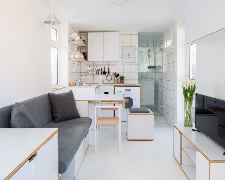 a white and grey living room filled with furniture next to a kitchen area that also has a dining table