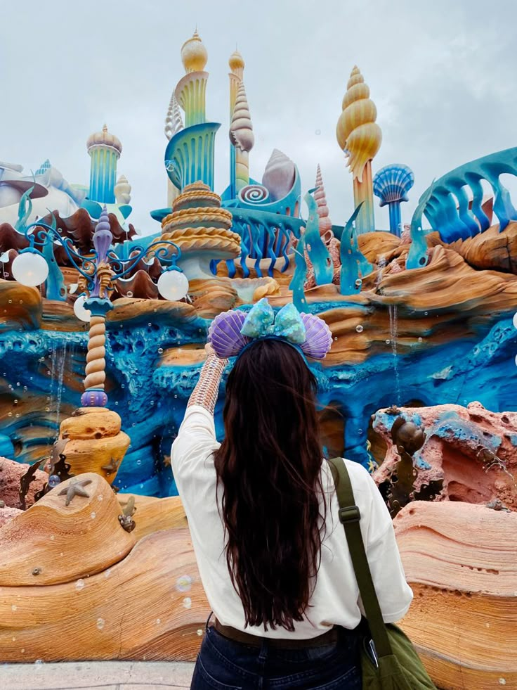 a woman standing in front of a blue and yellow theme park