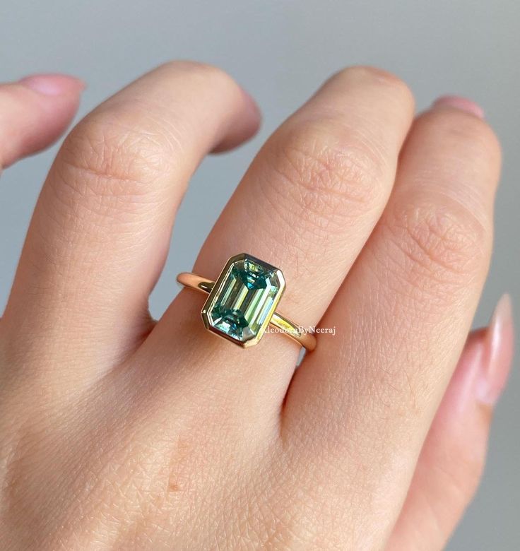 a woman's hand with a ring on it and an emerald stone in the middle