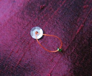 a close up of a piece of cloth with a small button on it and some thread