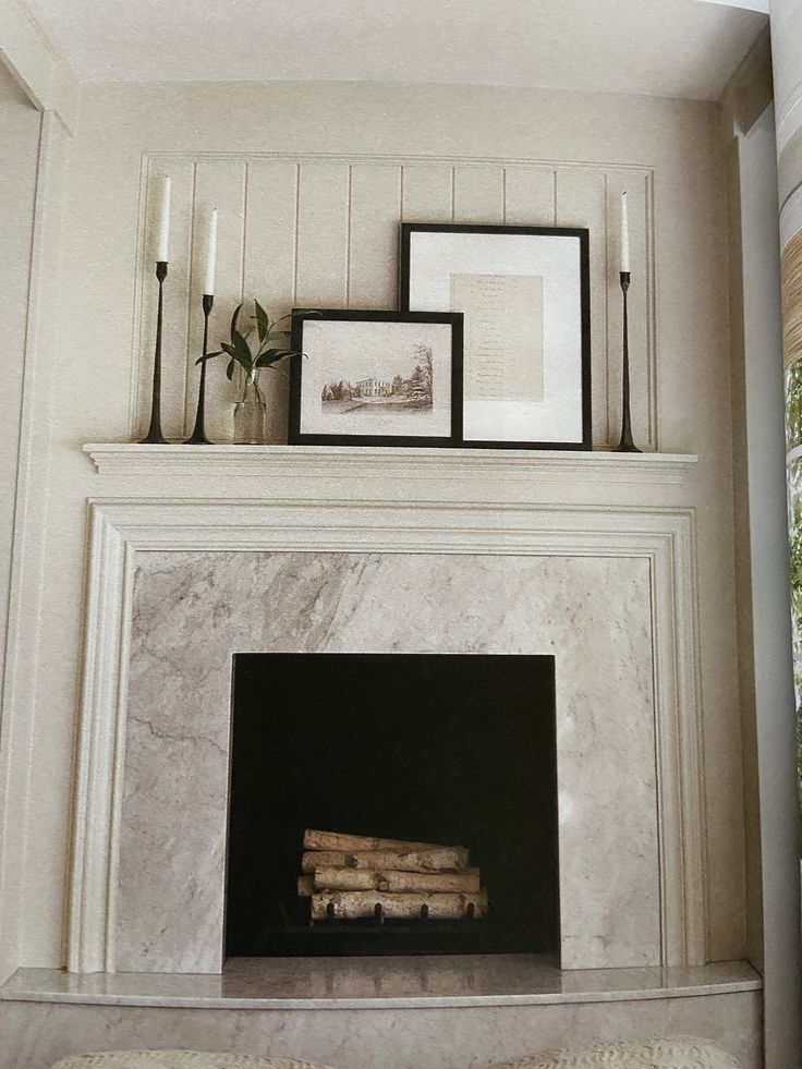 a fireplace with candles and pictures above it