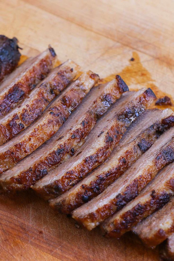 sliced meat sitting on top of a wooden cutting board