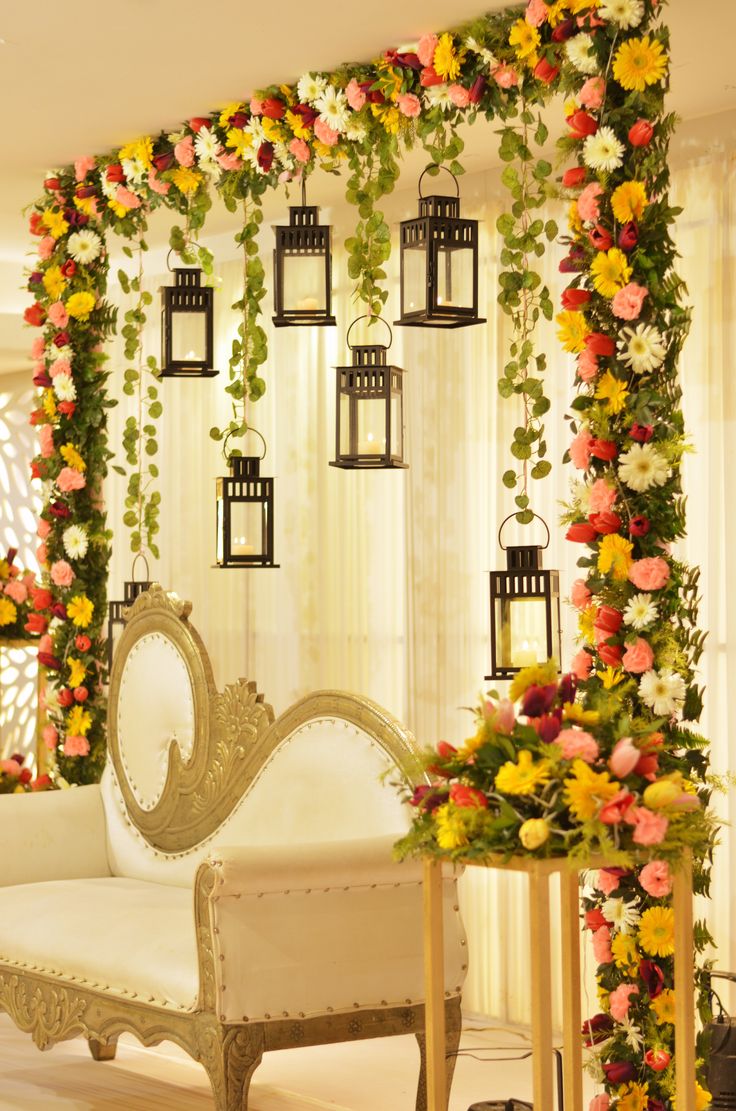 a white couch sitting in front of a wall covered in flowers and hanging lantern lights