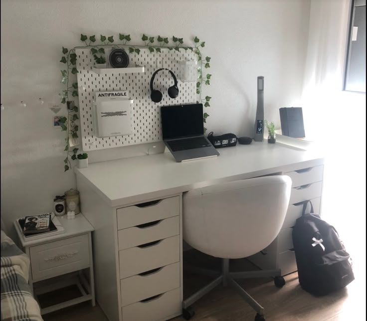 a white desk topped with a laptop computer next to a chair and wall mounted speakers