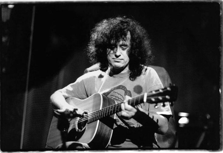 a black and white photo of a man playing an acoustic guitar