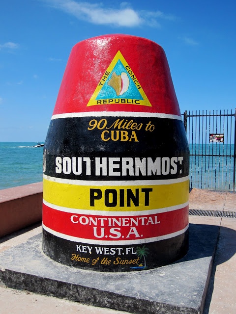 a large red and yellow sign sitting on the side of a road next to the ocean