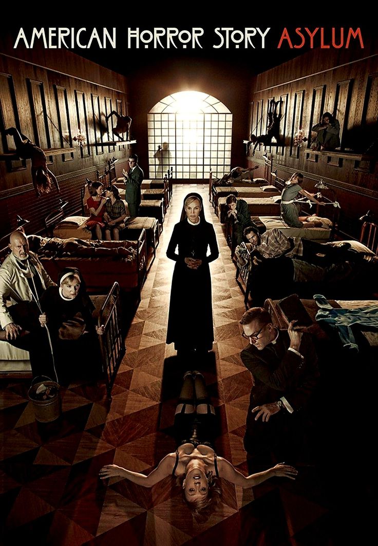 a woman standing in the middle of a room filled with beds and people laying on the floor