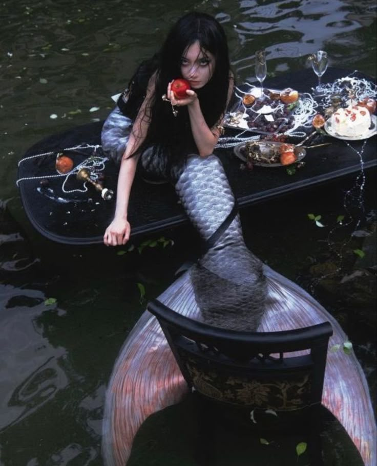 a woman sitting on top of a boat in the middle of water holding an apple