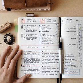 a person's hand on an open book next to a pen and other items