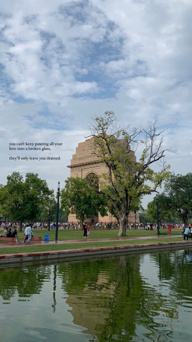 people are sitting on benches near the water in front of a building with a clock tower