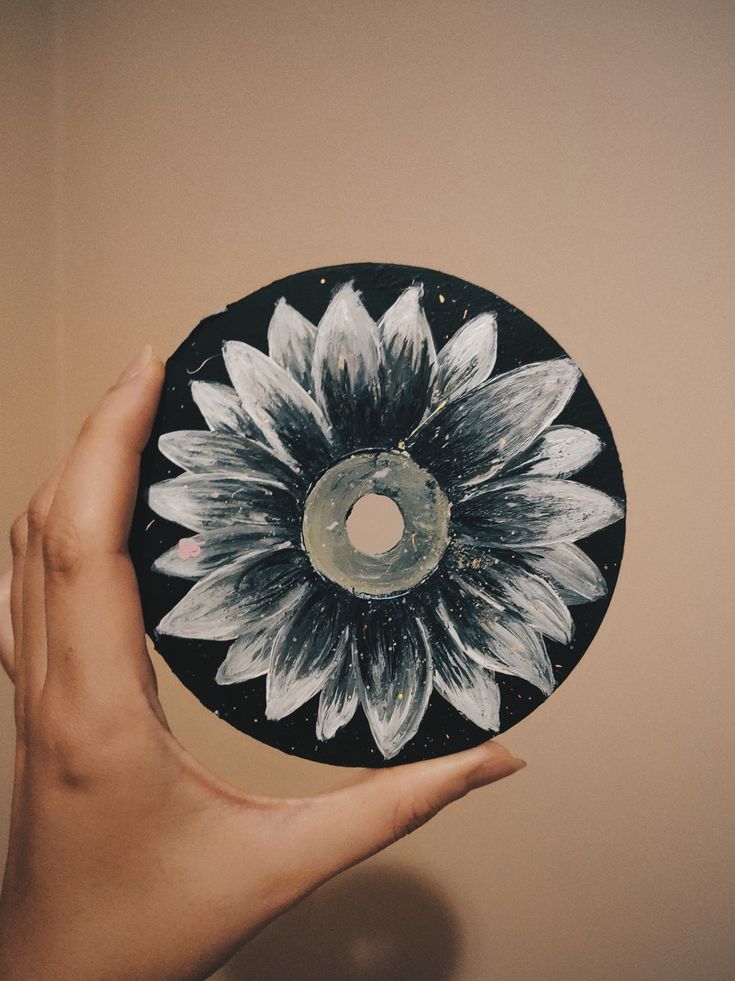 a person holding up a black and white disc with a sunflower on the front