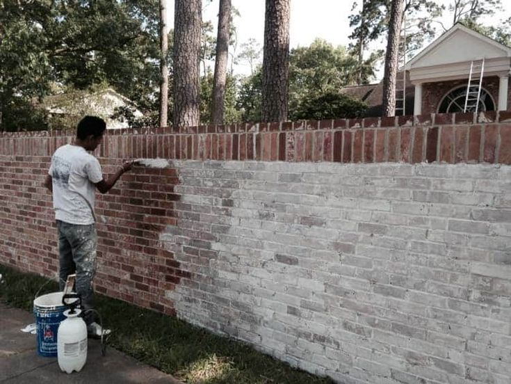 a man is painting a brick wall outside