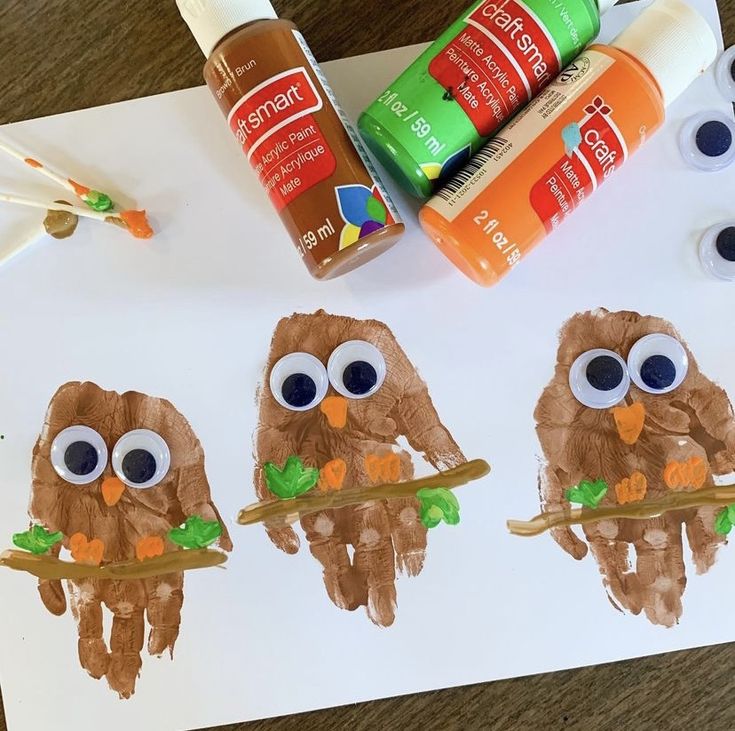 three little owls are sitting on a branch with leaves and carrots in front of them