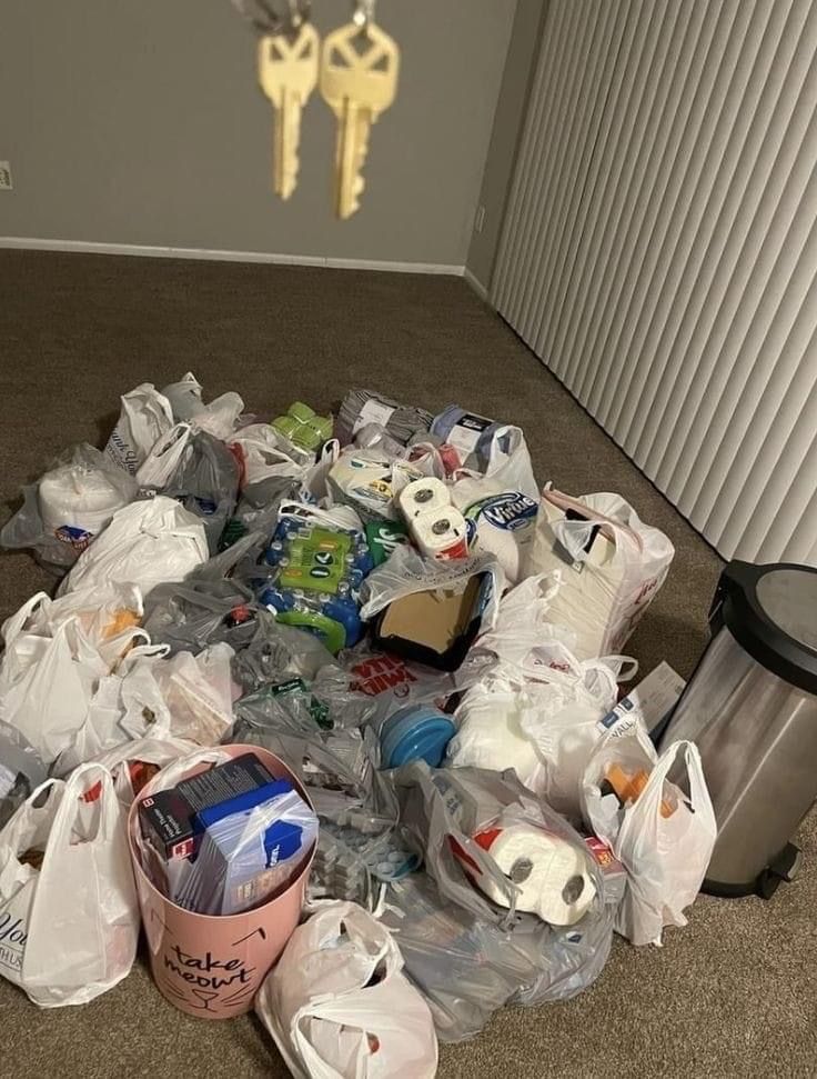 a pile of trash sitting on top of a floor next to a metal trash can