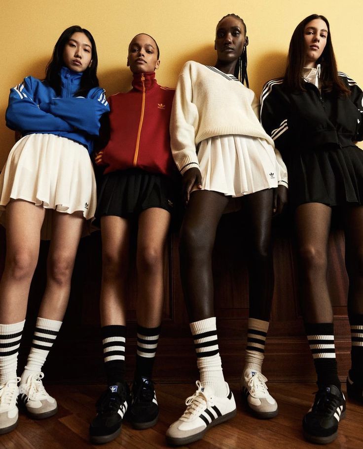 four women in short skirts and tennis shoes standing next to each other with their hands on their hipss