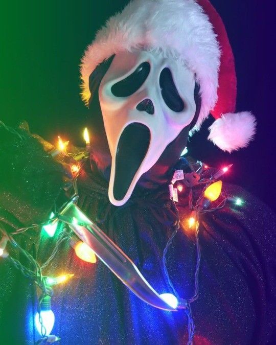 a person wearing a white mask with lights around his neck and head, in front of a dark background