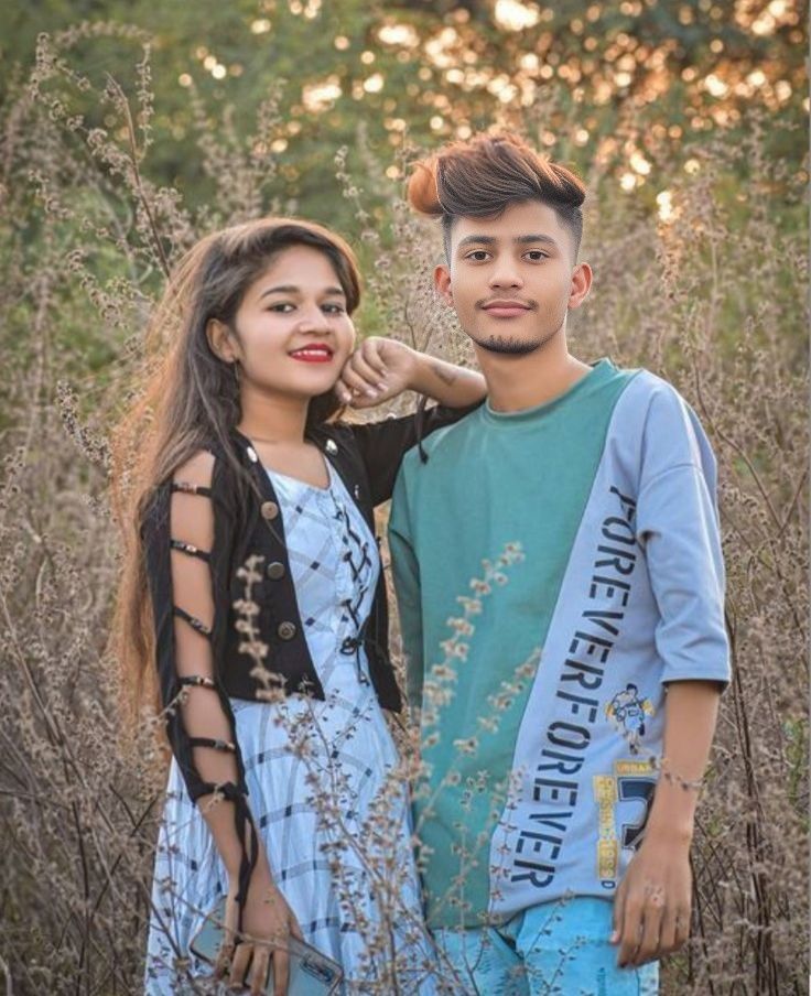 a young man and woman standing next to each other in tall grass with trees behind them