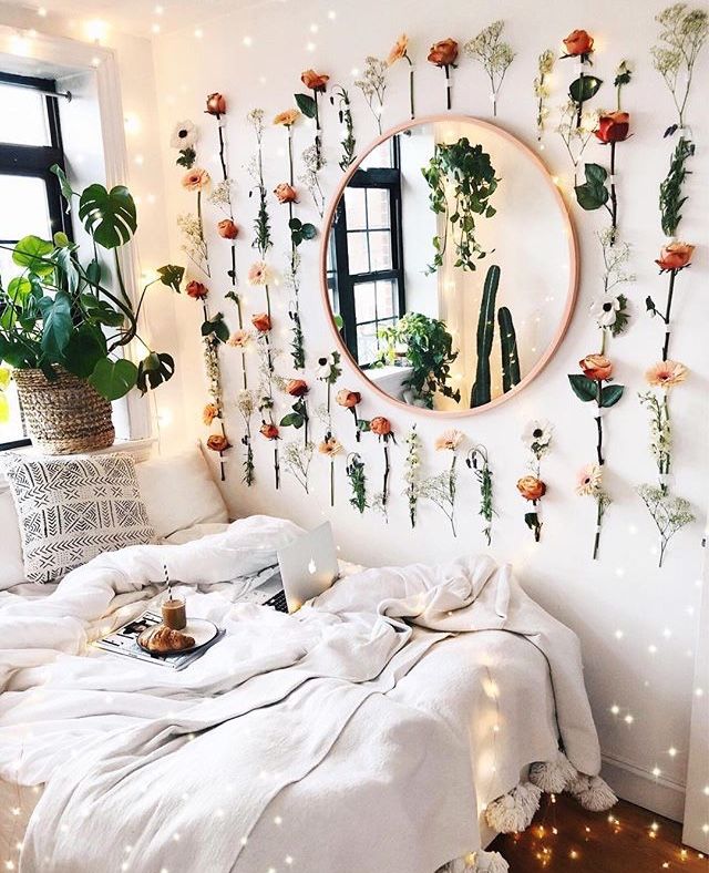 a bedroom with flowers on the wall and a bed in front of a round mirror