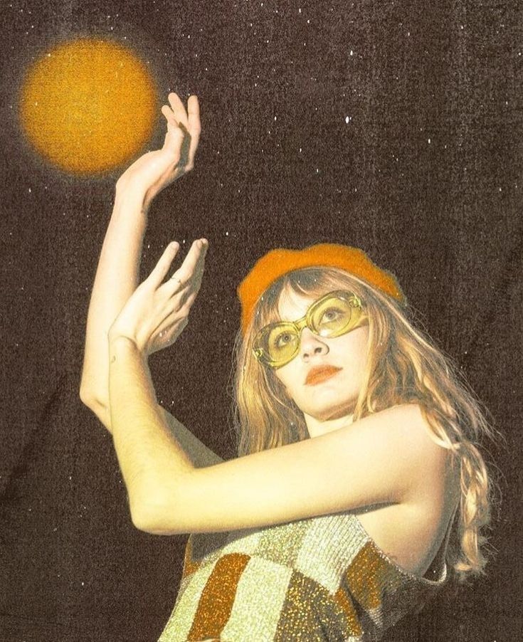 a woman wearing glasses and a red hat is holding a yellow ball in the air