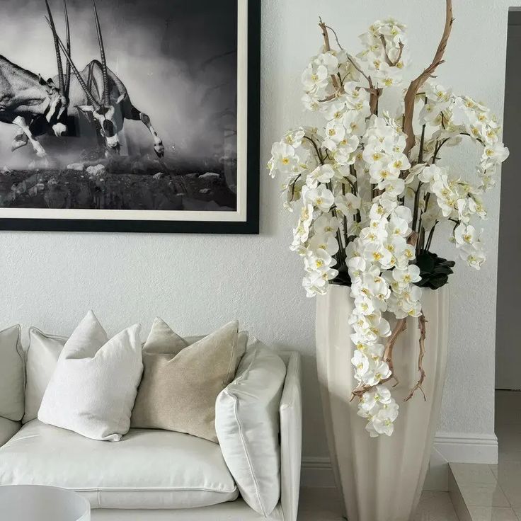 a white couch sitting next to a vase with flowers in it