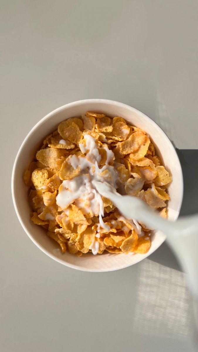 a bowl filled with cereal sitting on top of a white table next to a spoon