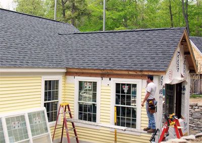 two men working on the roof of a small yellow house that's being built