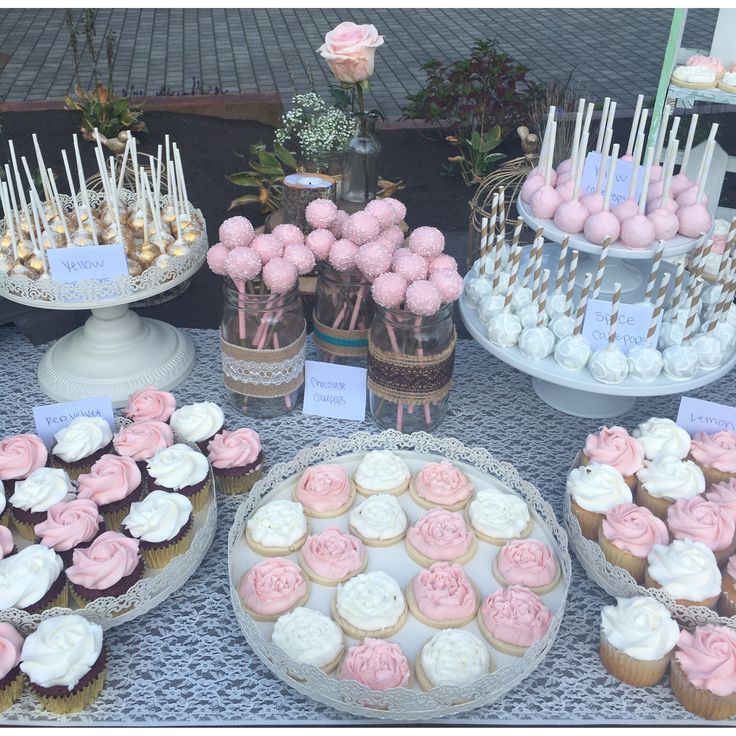 a table topped with lots of pink and white cupcakes