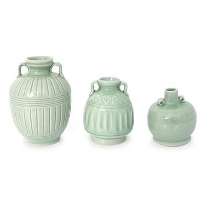 three green vases sitting next to each other on a white surface