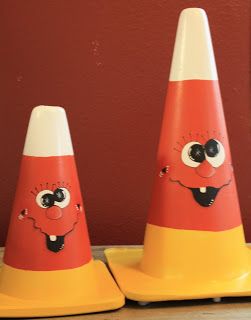 three traffic cones with faces painted on them sitting on a table next to a red wall