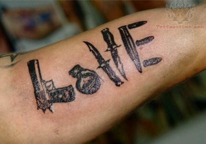 a man's arm with the word love written on it and two knives stuck in it