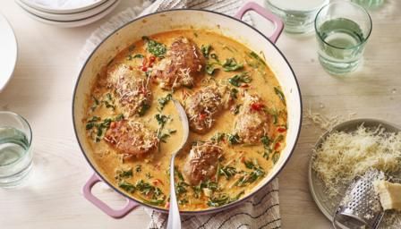 a pan filled with meatballs and vegetables on top of a table