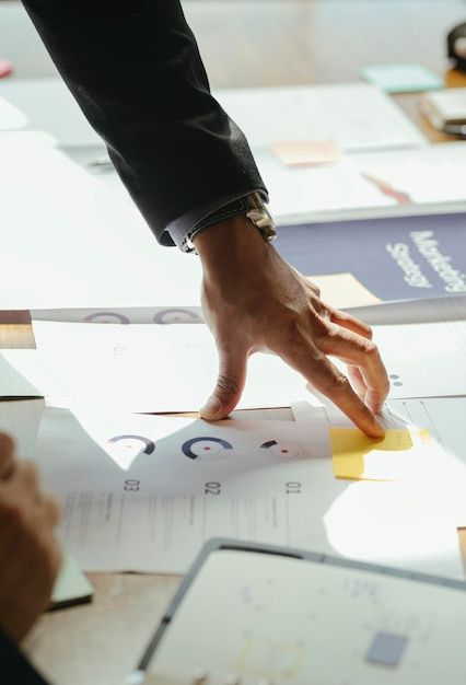 a person's hand on top of papers with other people looking at the paper