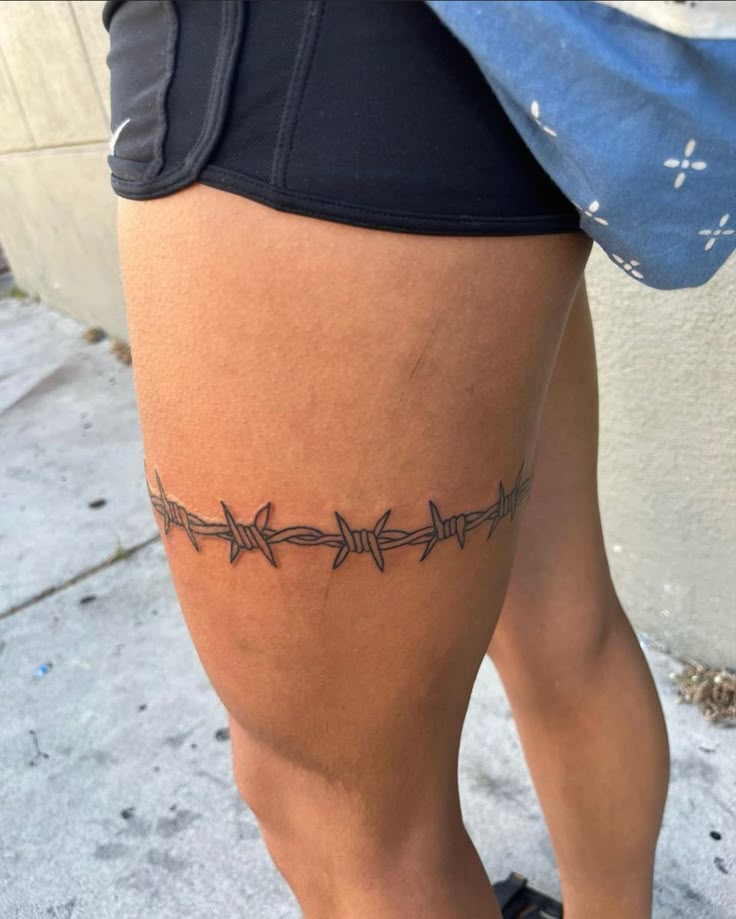 a woman's legs with barbed wire tattoo on the side of her leg,