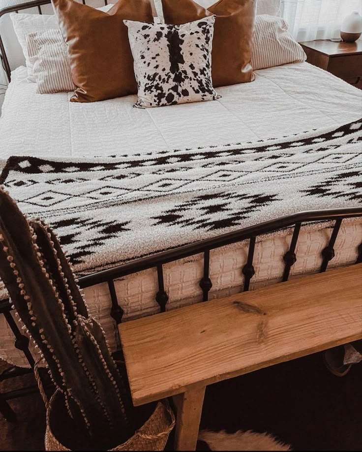 a bed with two pillows and a wooden bench in front of the headboard,