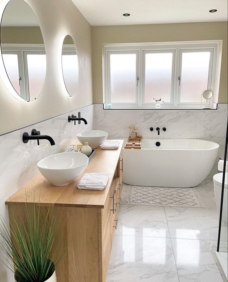 a bathroom with two sinks and a bathtub in the middle, surrounded by three round mirrors