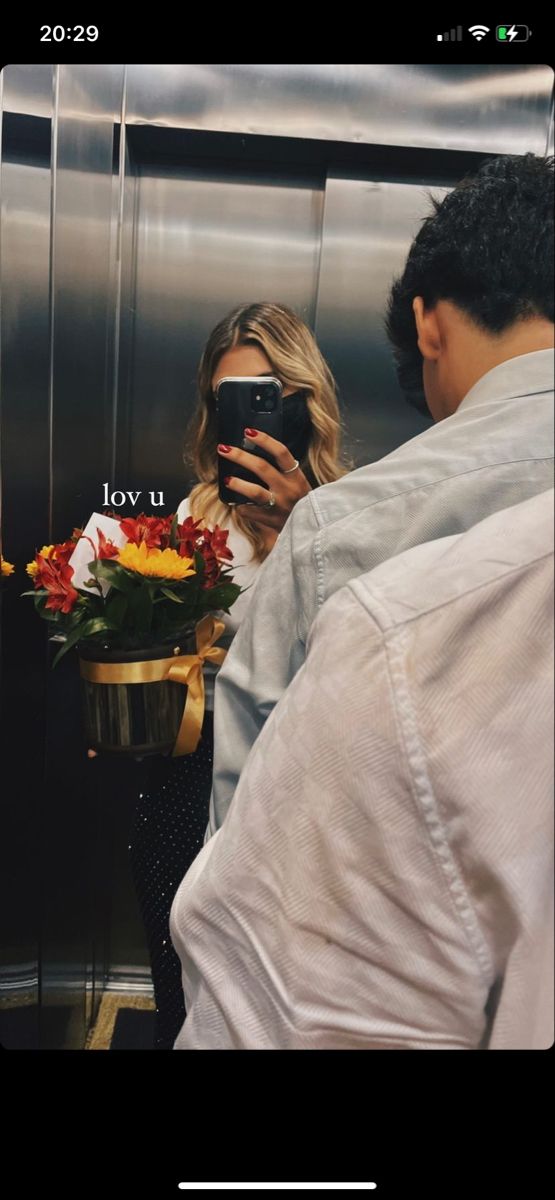 a woman taking a selfie with her cell phone in front of an elevator door