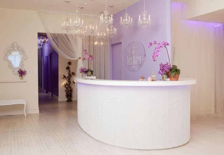 a white reception table with chandeliers hanging from it's ceiling and lights on either side