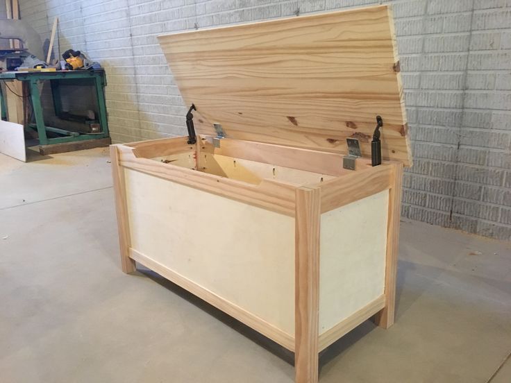 a large wooden box sitting on top of a floor next to a brick wall with tools in it