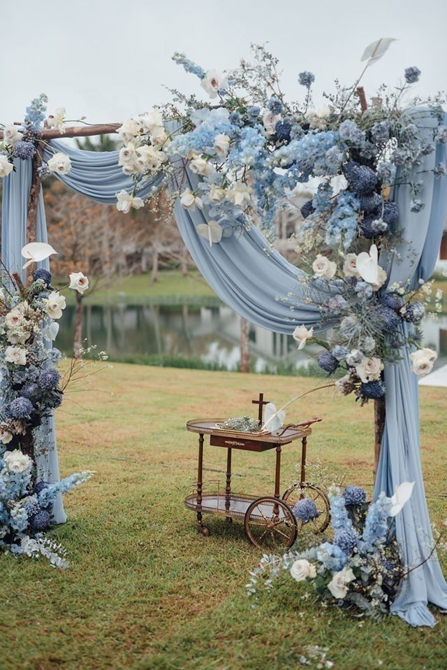 a blue and white wedding arch decorated with flowers