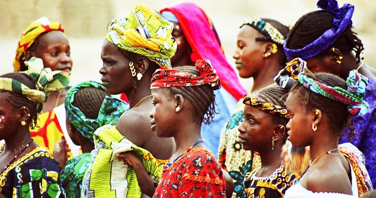 a group of women in brightly colored headdresses and scarves standing next to each other