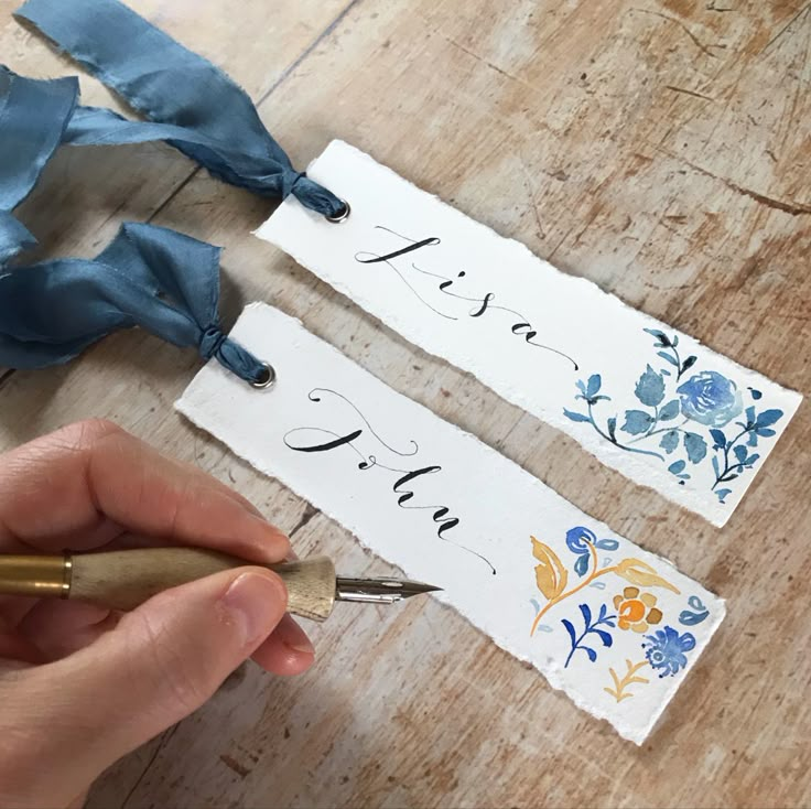 someone is writing on some paper with a fountain pen and blue ribbon tied around them