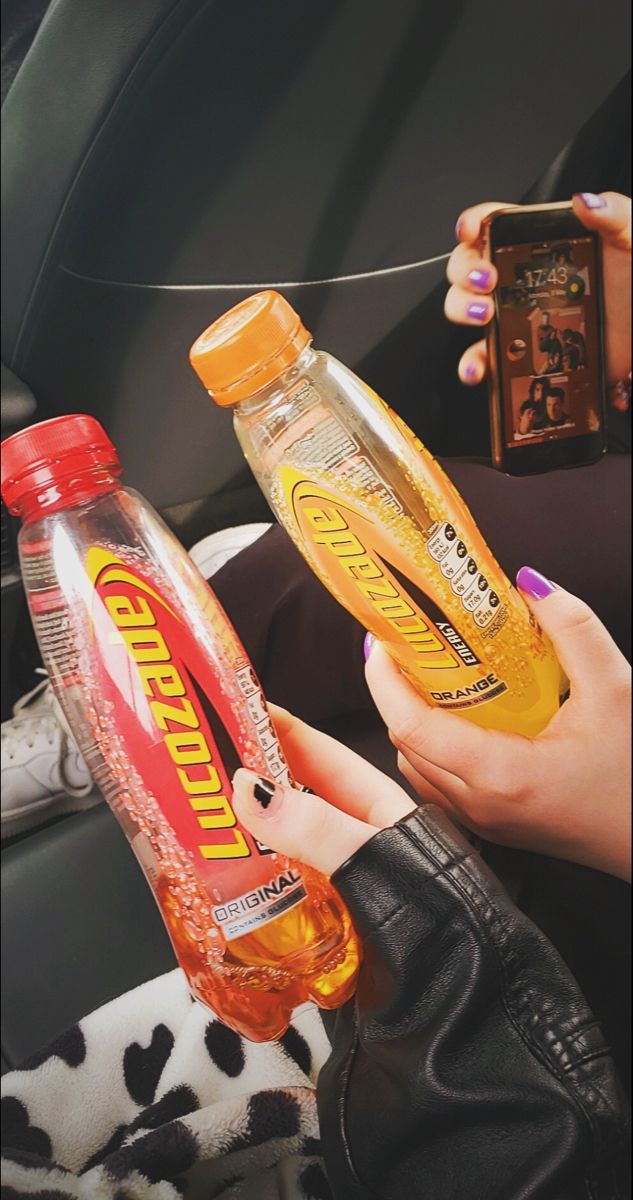 a woman is holding two bottles of mouthwash in her hand while sitting in the car