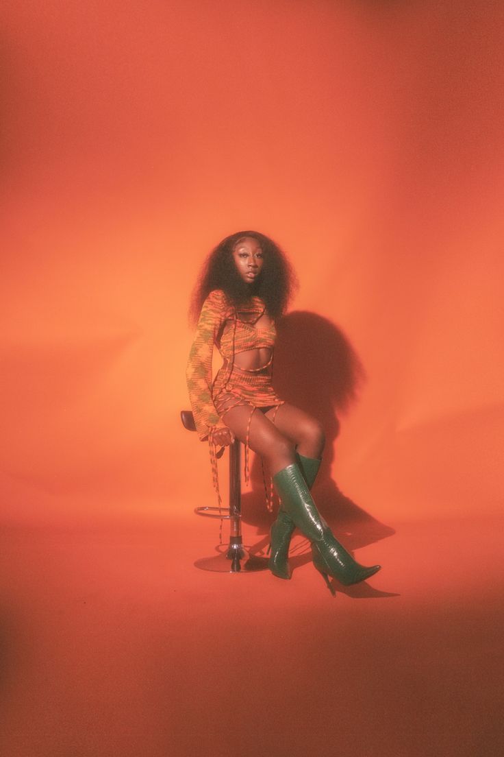 a woman sitting on top of a bike in front of an orange wall with her legs crossed