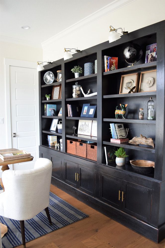 a living room with black bookcases and white chairs