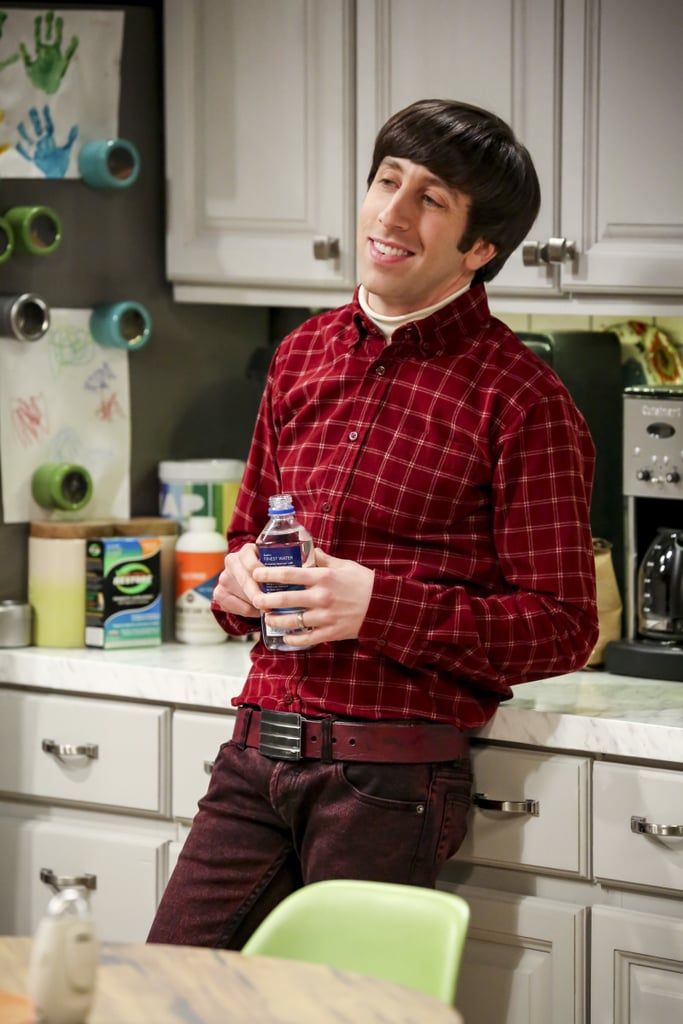 the young man is sitting on the kitchen counter and holding a bottle in his hand