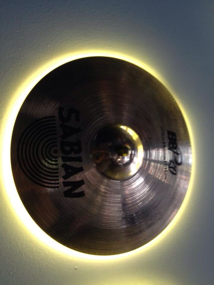 a light that is on the side of a wall next to a cymbal